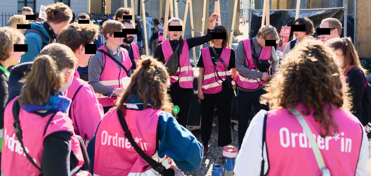 Ordner:innen in pink vests having a meeting before a demo.