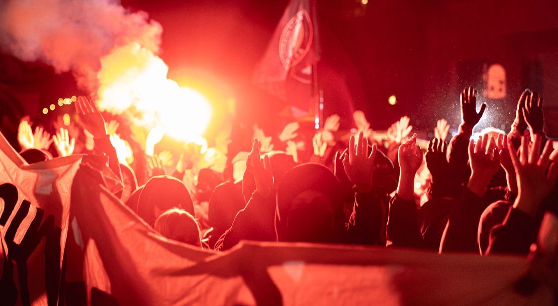 Masked protesters hold flares and smoke torches.